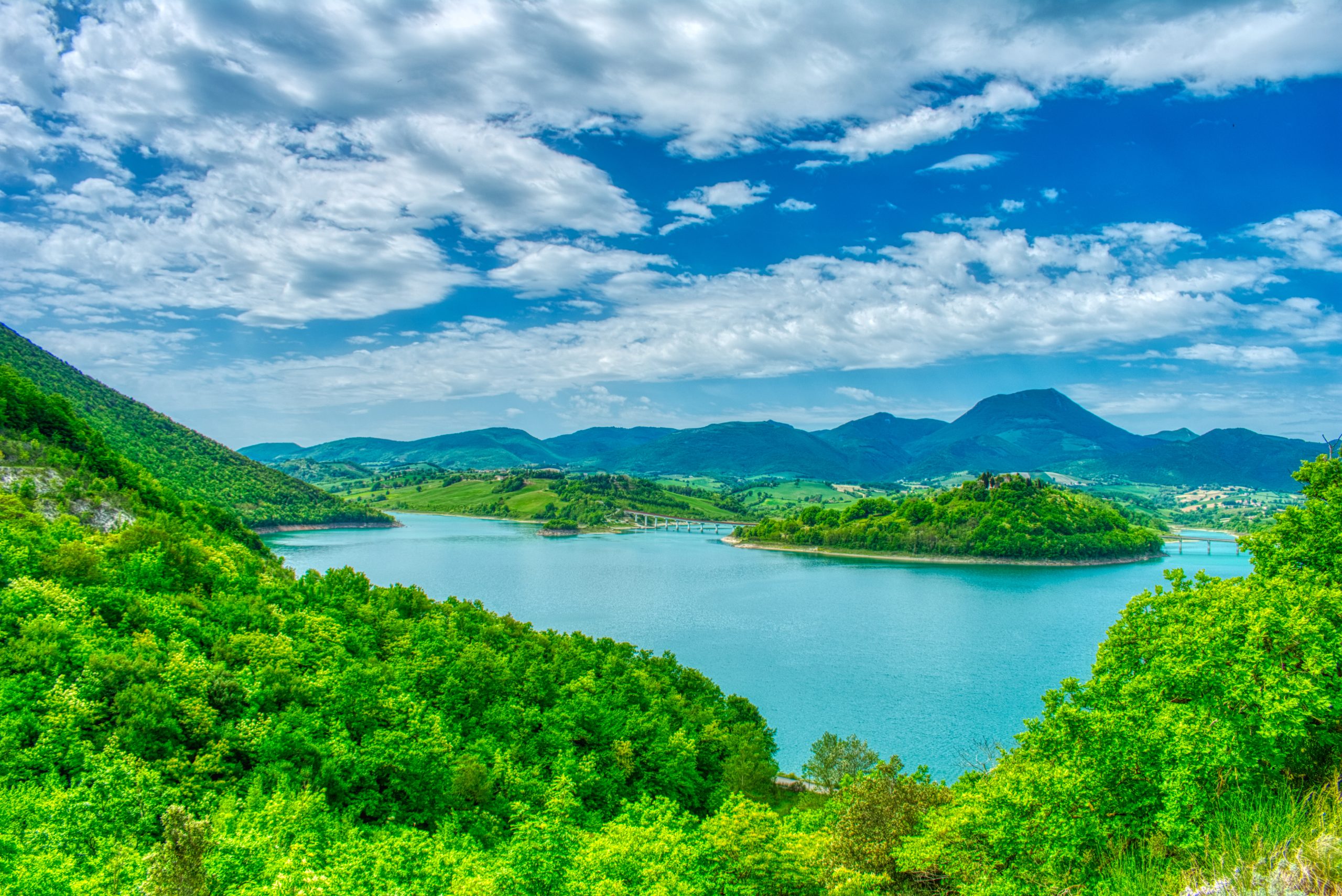 Panoramic view of Cingoli lake with blue sky and green and colorful mountains in summer